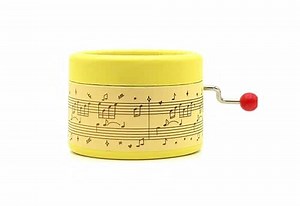 Yellow music box decorated with musical script and Happy Birthday melody on a hand crank.
