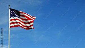 American flag waving in the wind in slow motion, with vibrant red white and blue colors against blue sky, with copy space. Stock Video