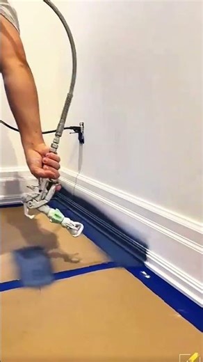 Spraying dark paint smoothly on wooden baseboard