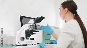Scientist in a modern medical lab examines molecular samples under a microscope. Microbiologist works with advanced technological equipment in a state-of-the-art laboratory