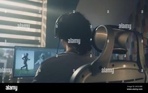 Back view of man in headphones sitting at the table and creating video game hero and 3D animation in professional computer program, while working remotely at home Stock Photo - Alamy