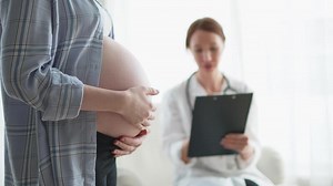 Pregnant woman hands touching big belly in doctor office. Female doctor examining pregnant woman. Gynecologist doctor consulting patient about pregnancy in hospital. Visit to doctor medical checkup