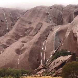It's raining on the rock! Uluru has been turned into a waterfall as a rare dry season rainband moves across central Australia. 💧 | Courier Mail