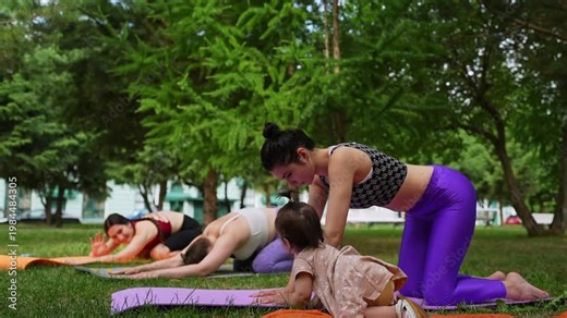 Mother and daughter practicing downward dog yoga pose together in orange mats in city park. Downward dog, yoga, mat, mother, daughter, city park.