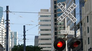 Level crossing warning signal in USA. Crossbuck notice and red traffic light on rail road intersection in California. Railway transportation safety symbol. Caution sign about hazard and train track.