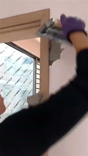 smoothing cement mixture into door frame gaps using a hand scraper tool neatly