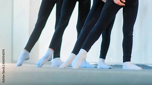 little ballet dancers in black tracksuits exercise stretching legs at class for beginners in studio slow motion close view