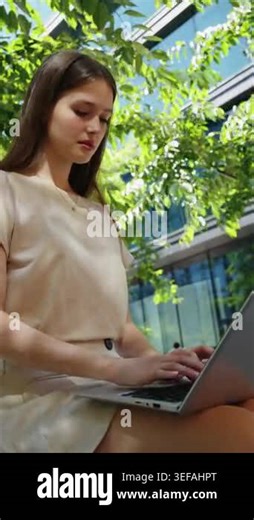 Serious female freelancer working on computer project on sunny summer day. Concentrated girl coding or writing email near business center Stock Video Footage - Alamy