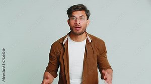 Irritated angry Indian man screams from stress tension problems feels horror hopelessness fear surprise shock expresses rage nervous, quarrel. Arabian young guy isolated on gray studio background