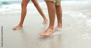 Low section of couple walking barefoot on the beach 4k