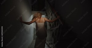 Scared woman in a nightgown runs up the stairs running away from home.