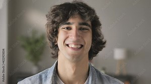 portrait of confident arab young man smiling to the camera indoors,handsome middle eastern male student look at the camera close up head shot blurred background