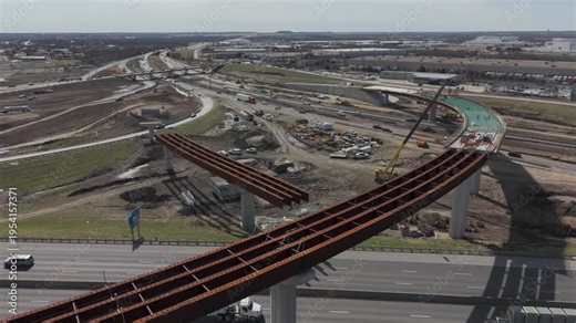 Denton, Texas USA – February 18, 2026: Aerial view of a highway interchange under construction with elevated ramps, bridge supports, and vehicle traffic on surrounding roadways.