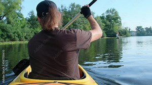 Man kayaks on lake maneuvering gracefully with paddle. He fully embraces excitement of water sports while on vacation far from city