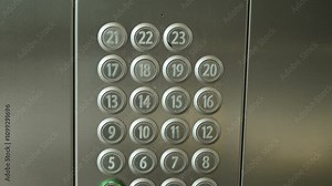 Close up view of elevator panel with buttons numbered from 1 to 23 on steel wall. Each button has braille numbers below, indicating accessible design for visually impaired users.