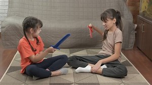 Children fight with sword. Two joyful children fight with blue and red swords on the floor.