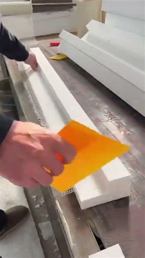 Attaching fiberglass mesh to white foam profiles with plastic scraper
