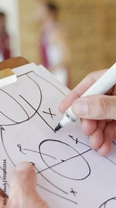 Hands of basketball coach drawing diagram on clipboard