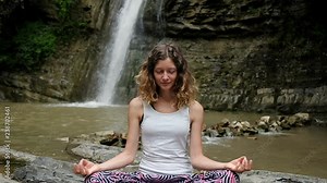 Happy girl meditates in the lotus position and opens her eyes while awakening from the practice, slow motion