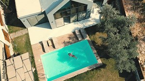 Aerial view of luxury pool villa and woman swimming at the pool.