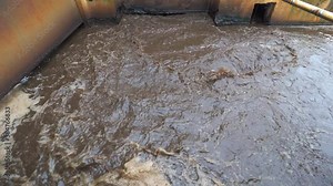 Thick sludge mixture in channel of wastewater treatment plant. Tanks for aeration and biological purification of sewage waste water. Activated sludge industrial wastewaters process.