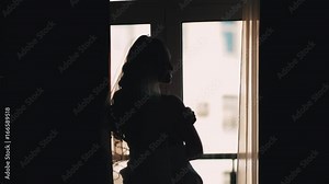 Silhouette of bride woman in vail waiting for groom in front of window in dark room an wedding day
