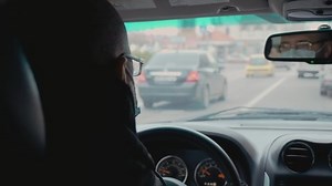 Man in protective medical face mask driving car and reflecting in rear view mirror. Concept of health savings during world wide pandemic of COVID
