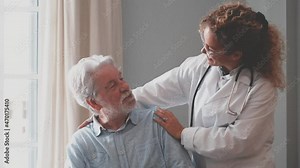 Young female doctor checking and helping senior man at his home. Doctor helping senior patient and giving care, sitting of sofa. Female home caregiver with retired old man at home