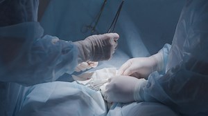 Suturing during surgery. Action. Hands of professional surgeons quickly cope with suturing. Surgeon ties knots for stitches on open wound