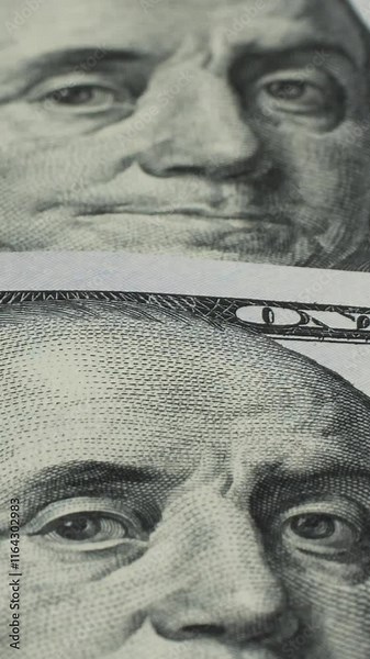 A close-up view of Benjamin Franklin's portrait on the hundred dollar bills reveals the fine details of the engraving and the texture of the paper. Vertical footage