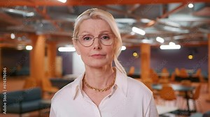 Confident female office worker wears reading glasses at conference video call, looking at laptop computer webcam. Businesswoman customer service manager speaking webcam communicating in distance 4K