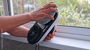 A man installs cleaning textile sponges on a robot window cleaner