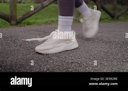 Close-up of a runner's hands tying the laces on a white sneaker before jogging on an asphalt path in a park Stock Video Footage - Alamy