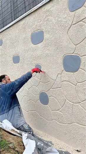 A Worker Texturing and Defining the Cobblestone Pattern on an Exterior Wall