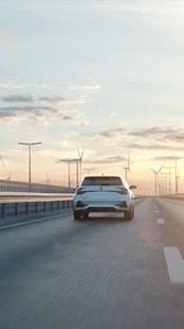 Auto-conducción de coche eléctrico autónomo a lo largo de un puente o autopista costera con turbinas de viento en el fondo. Concepto de energía sostenible. Animación 3D realista de alta calidad. Vertical Video