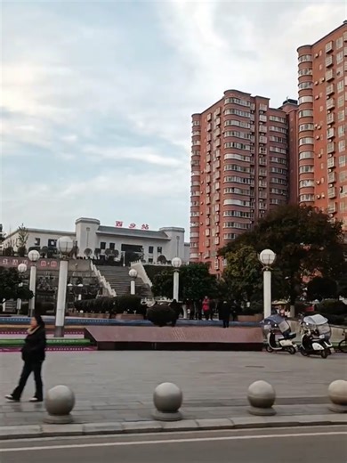 This is Xixiang County, China. 🇨🇳 Across the road is a small public square. 🏙️ Right above it stands the local train station 🚉 And on the right, two high-rise residential buildings. 🏢🏢 Everything is close together here — transportation, housing, and public space all in one view. Is your city designed like this too? 🌍 中文说明： 这里是中国西乡县。 马路对面是一座小型广场，广场上方就是当地的火车站。🚉 右边是两栋高层住宅小区。🏢 交通、居住、公共空间都集中在一起。 你们那里也是这样的城市布局吗？ #China #XixiangCounty #TrainStation #CityView #UrbanLife