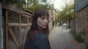 Pretty woman walking down an alleyway in an urban environment.