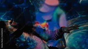 Young attractive woman dancing in the light of colorful projector pattern