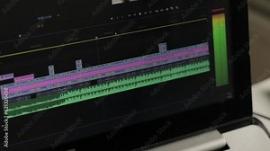Close up of a laptop with film and video editing software with a timeline and moving audio display. Selective focus.