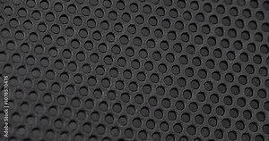 Black perforated surface texture. Close-up view of a black perforated surface with a repeating hole pattern, creating a textured and industrial look.