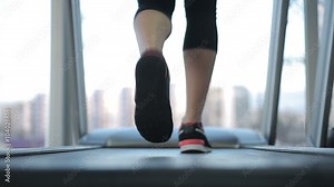 Back view of female legs walking and running on treadmill in gym, woman training
