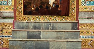 A young Buddhist novice steps into a richly decorated temple for the evening chanting ritual, joining senior monks in a traditional act of devotion and community.