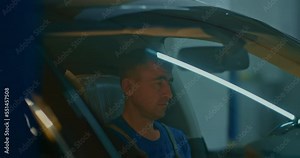 Auto mechanic who uses a computer diagnostic program during the repair of a car in the workshop. Checks for vehicle malfunctions on a digital tablet. Car service.