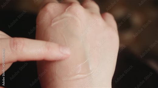 A close-up of fingers applying and spreading pain-relieving ointment onto a hand. Concept for arthritis treatment and joint care for pain. High quality 4k footage