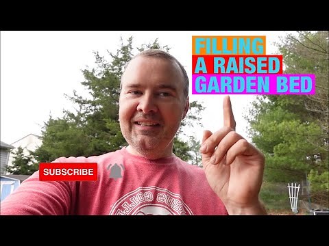 Filling a raised garden bed with a mix of compost, peat moss, and vermiculite.