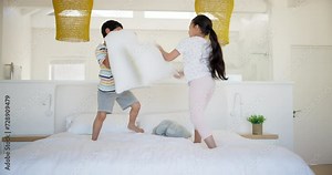 Kids, girl and boy with pillow fight on bed, laughing and playful with bonding on holiday in house. Children, bedroom and excited for comic game, brother and sister in morning, happy and family home