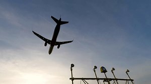 Overhead flying aircraft landing at sunset. Modern large plane flies overhead.
