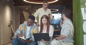 Diverse colleagues collaborate in a creative co-working space, using technology to solve problems.