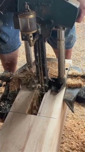 Cutting a large brown wooden log precisely using a professional electric chain mortiser machine tool