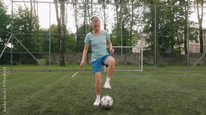 Portrait of a female soccer player on the football field. The woman, dressed in a soccer uniform, is kicking ball with her foot and looking into the camera.